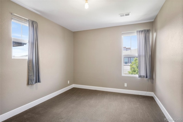 3450 Valentia St, Denver, CO 80238 - empty room featuring plenty of natural light, dark colored carpet, and baseboards