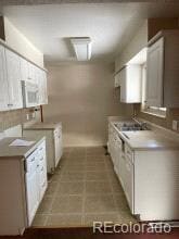 kitchen with tile patterned flooring, white cabinetry, and sink