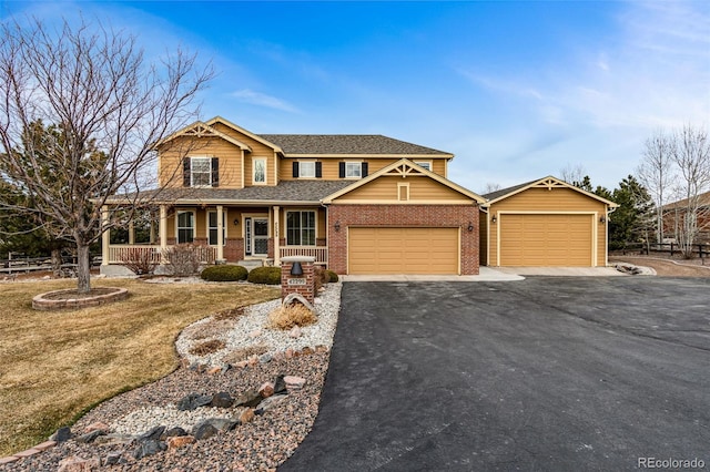 view of front of home with aphalt driveway, a porch, a shingled roof, a garage, and brick siding