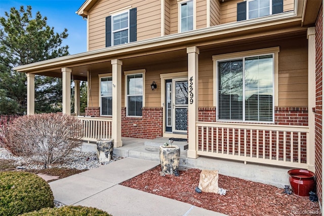 entrance to property featuring brick siding and covered porch