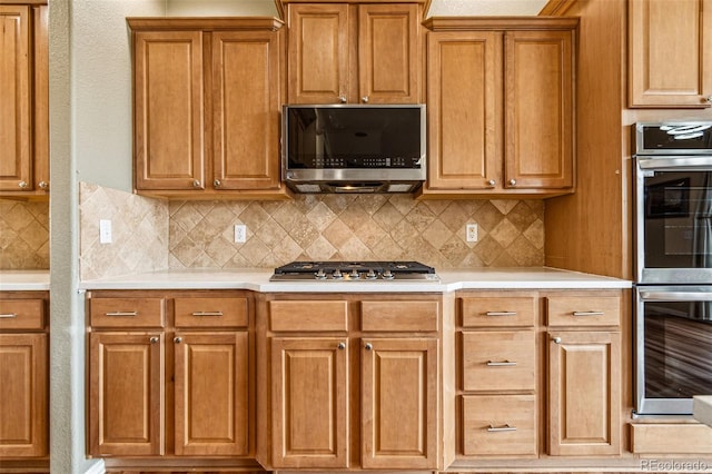 kitchen with decorative backsplash, brown cabinets, appliances with stainless steel finishes, and light countertops