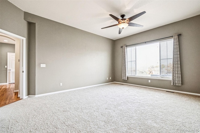 spare room with baseboards, visible vents, a ceiling fan, and carpet