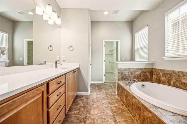 full bath featuring tile patterned floors, a walk in closet, visible vents, a garden tub, and vanity