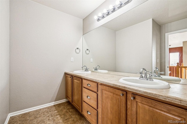 full bath featuring a sink, baseboards, and double vanity