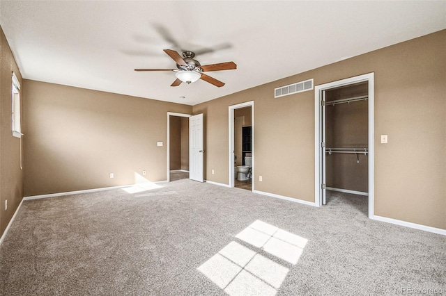 unfurnished bedroom featuring baseboards, visible vents, carpet floors, a closet, and a walk in closet