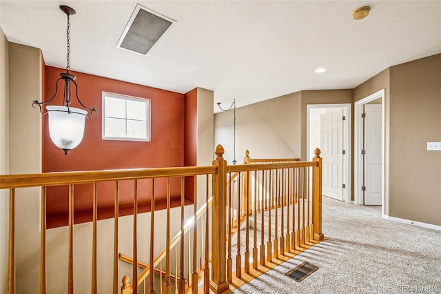 corridor featuring an upstairs landing, visible vents, baseboards, and carpet