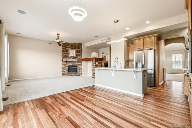 kitchen with ceiling fan, stainless steel fridge with ice dispenser, open floor plan, a breakfast bar area, and arched walkways