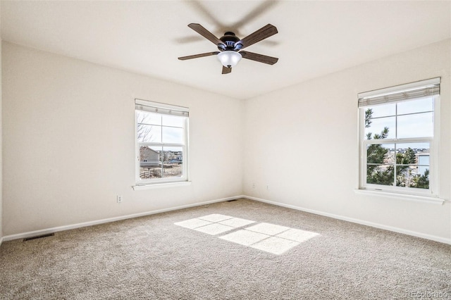 carpeted spare room with visible vents, a ceiling fan, and baseboards