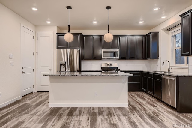 kitchen with sink, appliances with stainless steel finishes, a center island, and hanging light fixtures