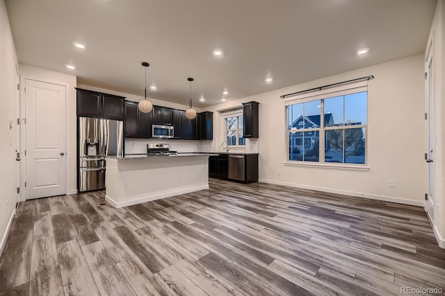 kitchen featuring dark hardwood / wood-style floors, stainless steel appliances, decorative light fixtures, and a kitchen island