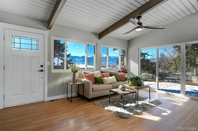 sunroom / solarium with a mountain view, ceiling fan, and vaulted ceiling with beams