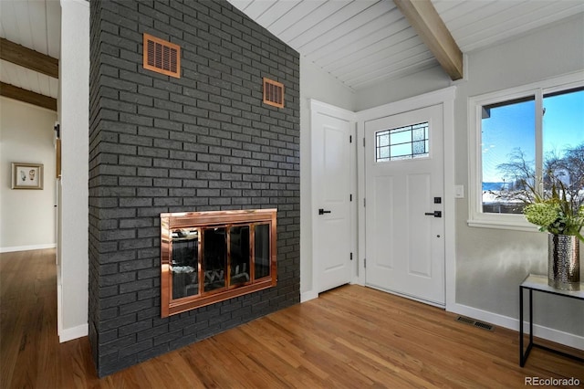 foyer featuring hardwood / wood-style flooring, a fireplace, and vaulted ceiling with beams