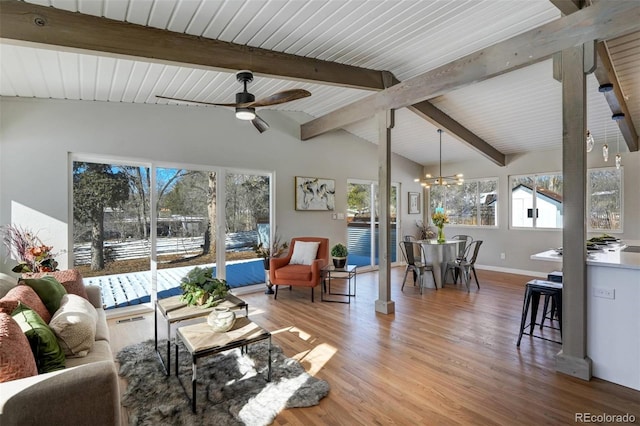 living room with vaulted ceiling with beams, ceiling fan with notable chandelier, and hardwood / wood-style floors