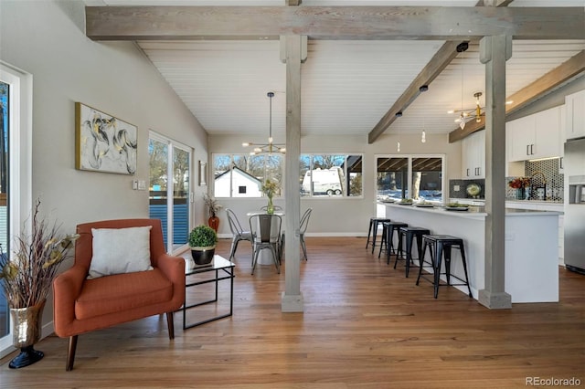 interior space featuring light wood-type flooring, lofted ceiling with beams, and a notable chandelier