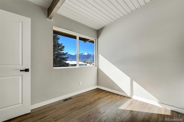 empty room featuring wooden ceiling, hardwood / wood-style floors, and beamed ceiling