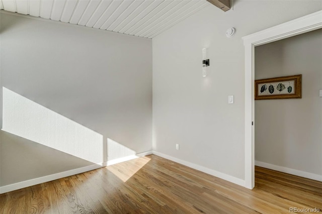 spare room with beam ceiling and light wood-type flooring