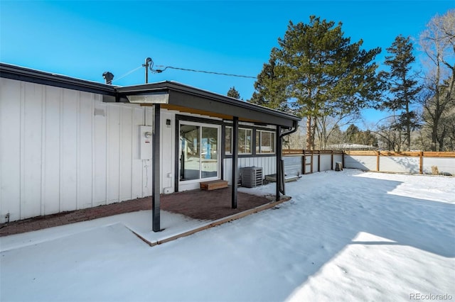 snow covered rear of property with central air condition unit