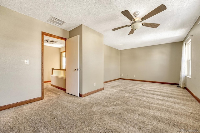 carpeted spare room featuring ceiling fan and a textured ceiling