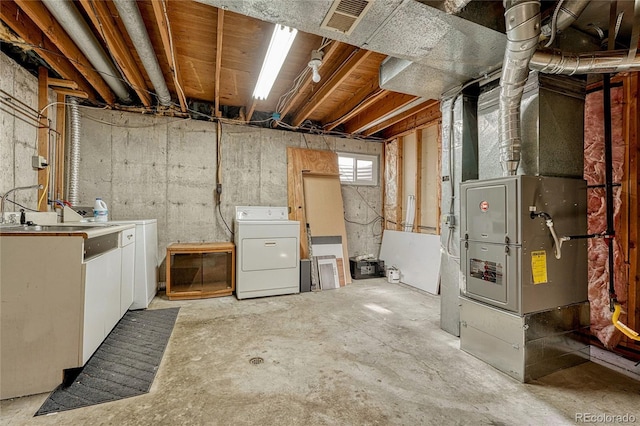 basement featuring heating unit and washer and clothes dryer