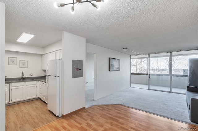 kitchen with white appliances, white cabinets, sink, light hardwood / wood-style flooring, and a textured ceiling