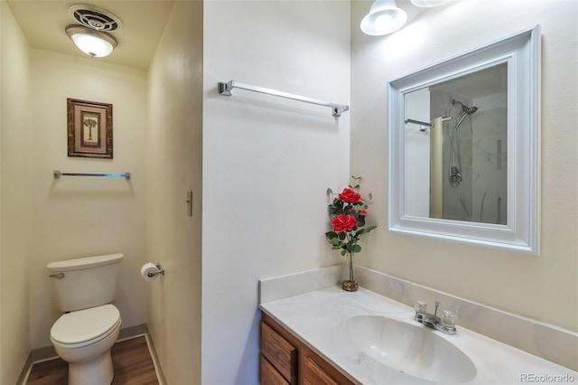 bathroom with wood-type flooring, vanity, toilet, and walk in shower