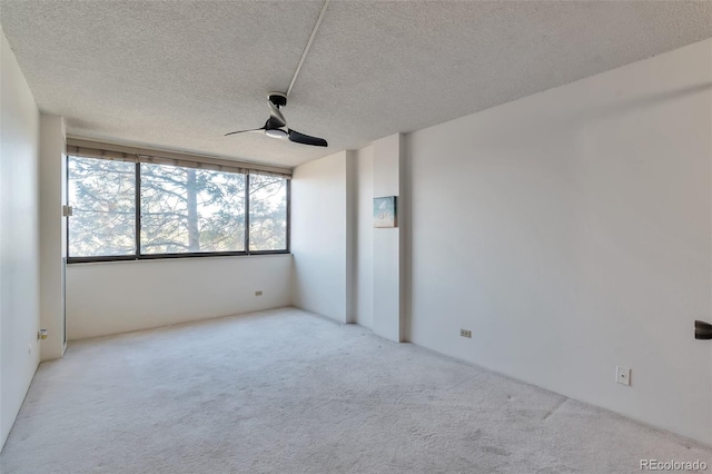 spare room featuring light carpet, a textured ceiling, and ceiling fan