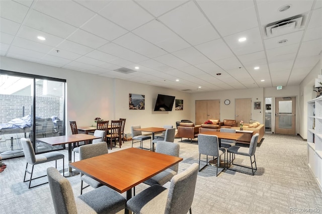 carpeted dining space featuring a paneled ceiling