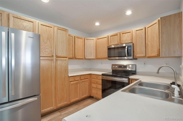 kitchen featuring appliances with stainless steel finishes, light brown cabinetry, sink, and light hardwood / wood-style flooring