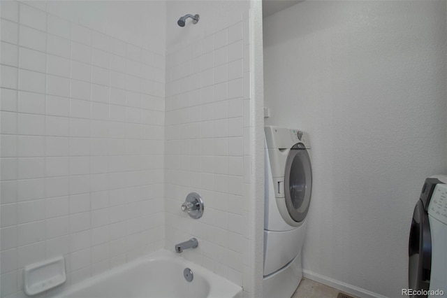 bathroom with tiled shower / bath combo and washer / dryer