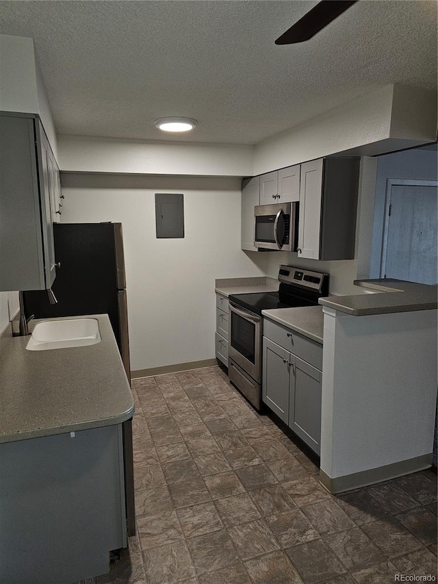 7000 W 20th Ave Unit 106, Lakewood, CO 80214 - kitchen featuring appliances with stainless steel finishes, a sink, gray cabinets, a textured ceiling, and baseboards