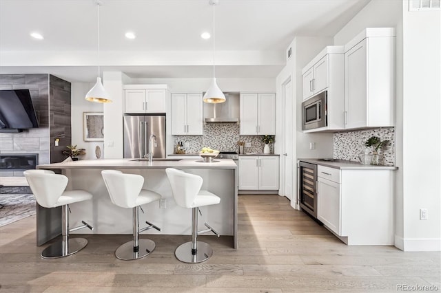 kitchen with white cabinetry, hanging light fixtures, wine cooler, and appliances with stainless steel finishes