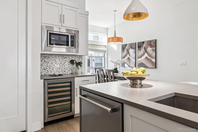 kitchen featuring white cabinets, pendant lighting, beverage cooler, and stainless steel appliances