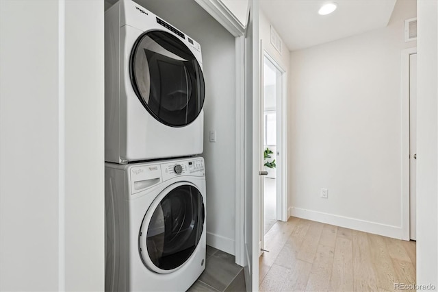 laundry room with stacked washer / drying machine and light hardwood / wood-style flooring