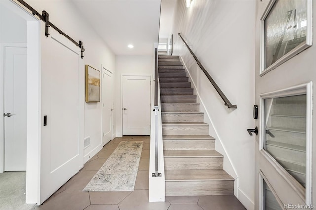 stairs featuring a barn door and tile patterned floors