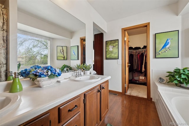 1055 Lindstrom Dr, Colorado Springs, CO 80911 - bathroom featuring wood finished floors, double vanity, a garden tub, and a spacious closet