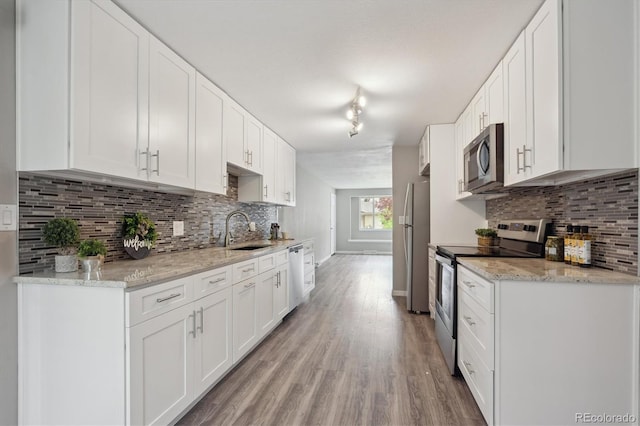 3685 Lewis St, Wheat Ridge, CO 80033 - kitchen with appliances with stainless steel finishes, a sink, light wood finished floors, and tasteful backsplash