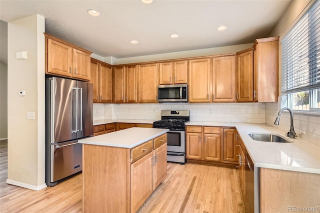 kitchen featuring a center island, backsplash, sink, light hardwood / wood-style flooring, and appliances with stainless steel finishes