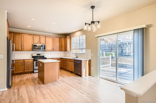 kitchen featuring a center island, sink, stainless steel appliances, light hardwood / wood-style floors, and decorative light fixtures