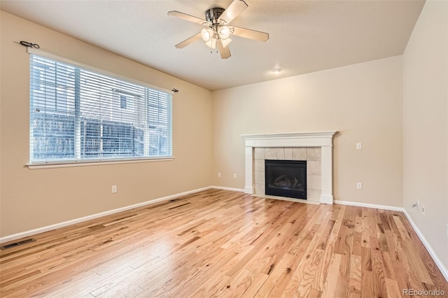 unfurnished living room featuring a tile fireplace, a wealth of natural light, and light hardwood / wood-style flooring