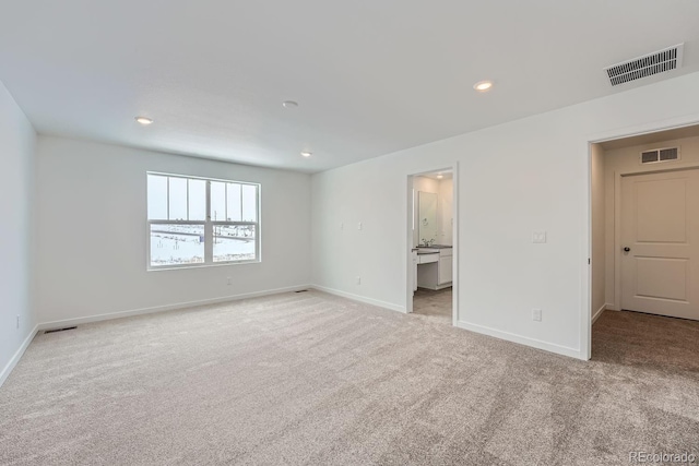 unfurnished bedroom with light carpet and connected bathroom