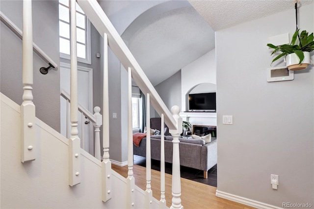 interior space with a textured ceiling, hardwood / wood-style flooring, and lofted ceiling