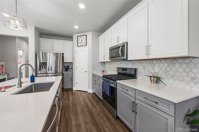 kitchen featuring stainless steel appliances, a sink, recessed lighting, dark wood-style floors, and backsplash