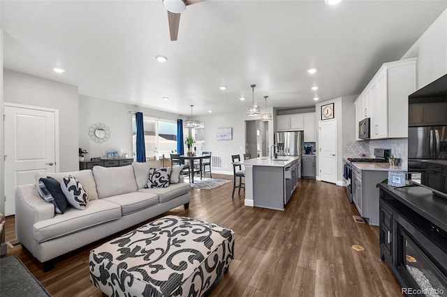 living area with recessed lighting, dark wood-type flooring, a ceiling fan, and baseboards