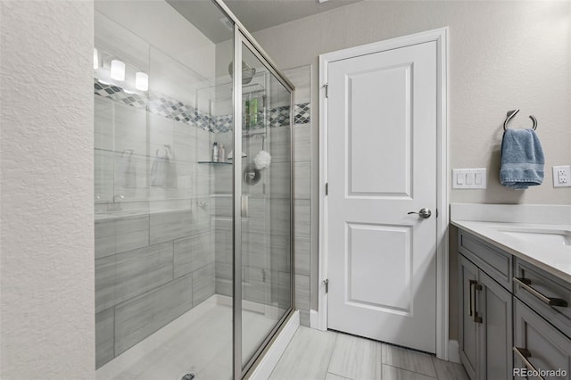 full bath with a stall shower, a textured wall, and vanity