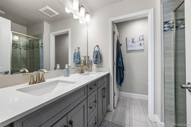 full bathroom with a stall shower, double vanity, and baseboards
