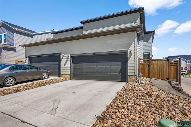 view of front facade with concrete driveway, fence, and an attached garage