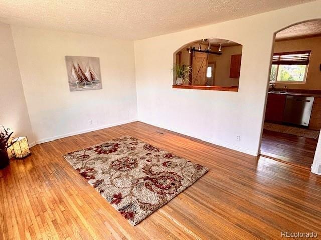 3531 E 91st Ave, Thornton, CO 80229 - spare room with wood finished floors, arched walkways, a textured ceiling, and baseboards