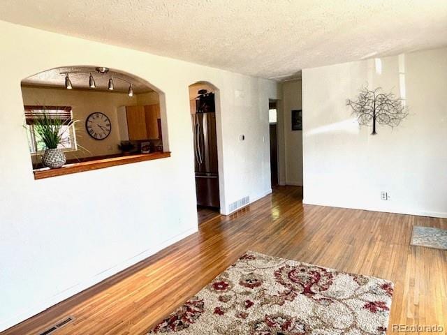 3531 E 91st Ave, Thornton, CO 80229 - empty room with wood finished floors, a textured ceiling, and arched walkways