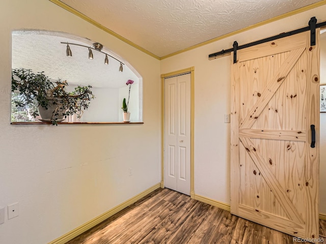 3531 E 91st Ave, Thornton, CO 80229 - unfurnished bedroom featuring wood finished floors, ornamental molding, a barn door, baseboards, and a textured ceiling
