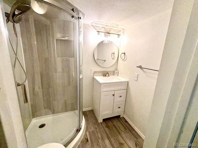3531 E 91st Ave, Thornton, CO 80229 - full bathroom featuring wood finished floors, a stall shower, vanity, baseboards, and a textured ceiling